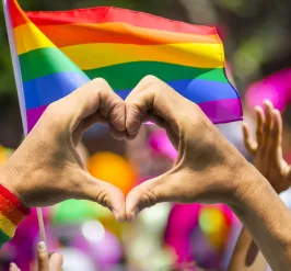 Heart hands in front of pride flag