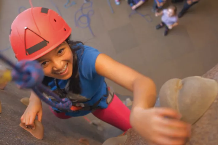 Girl climbing the rock wall