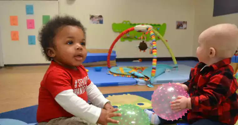 Two infants playing with balls