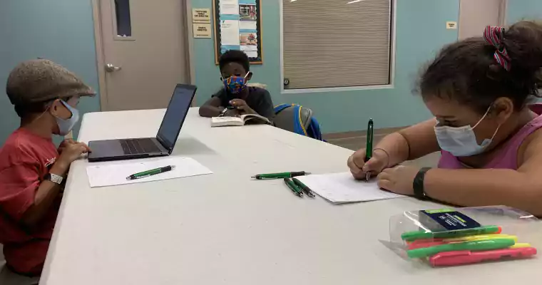Three kids in masks doing school work